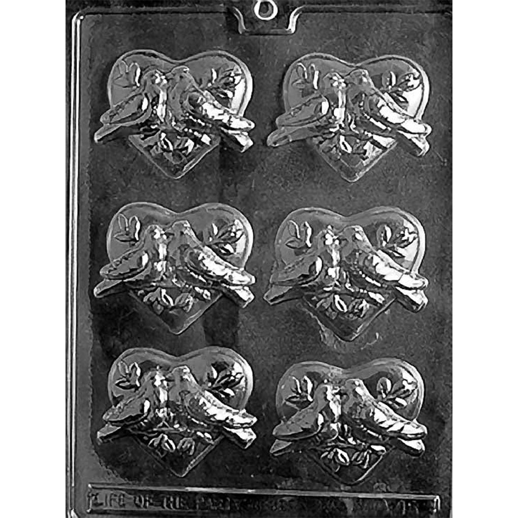 Clear chocolate mold with six heart-shaped cavities featuring pairs of detailed doves and leafy accents on a dark background.