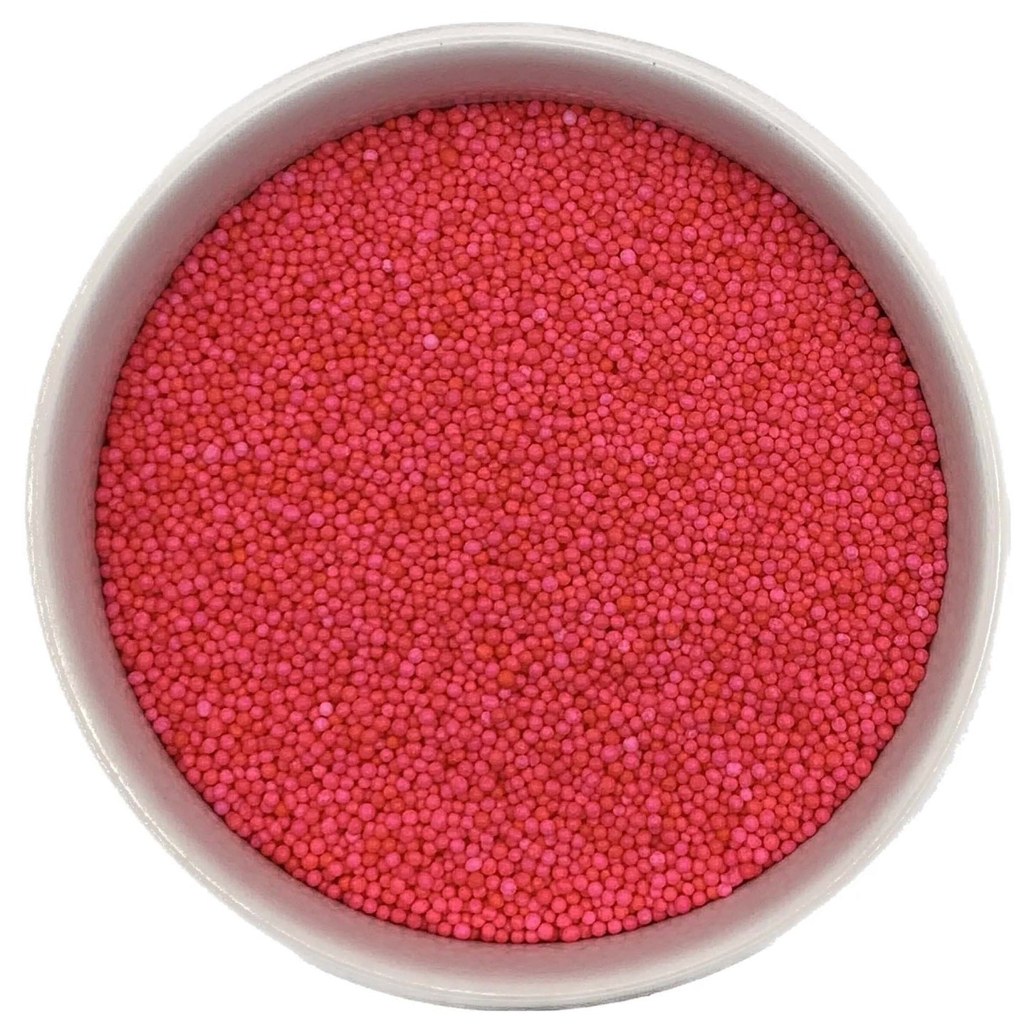 Top-down view of a white bowl filled with hot pink non-pareils, showing tiny round sprinkle beads in bright fuchsia and pink shades.