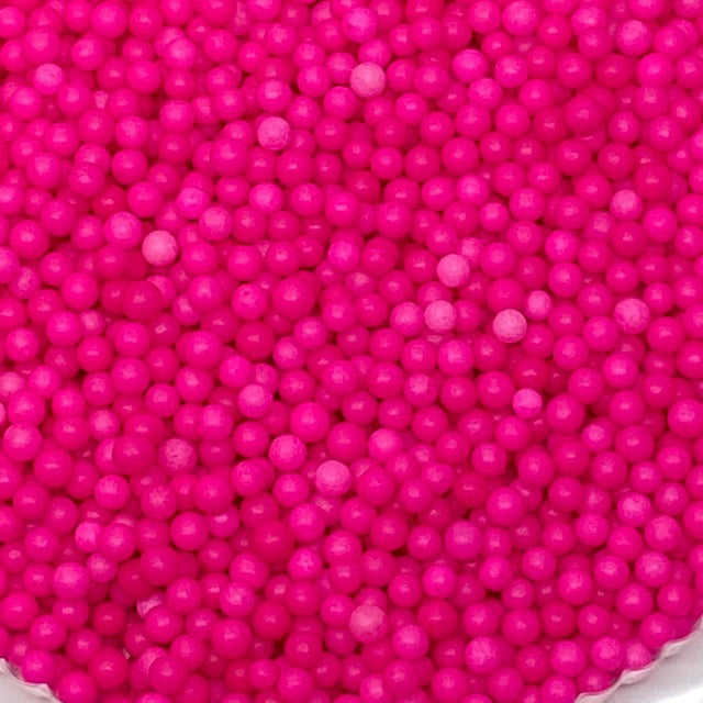 Close-up of 4mm hot pink sugar pearls in a clustered pile, ideal for decorating cakes, cupcakes, and cookies.