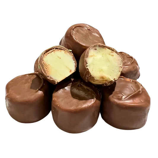 Stack of round chocolate-coated key lime candies, with two cut open to reveal a light green creamy center.