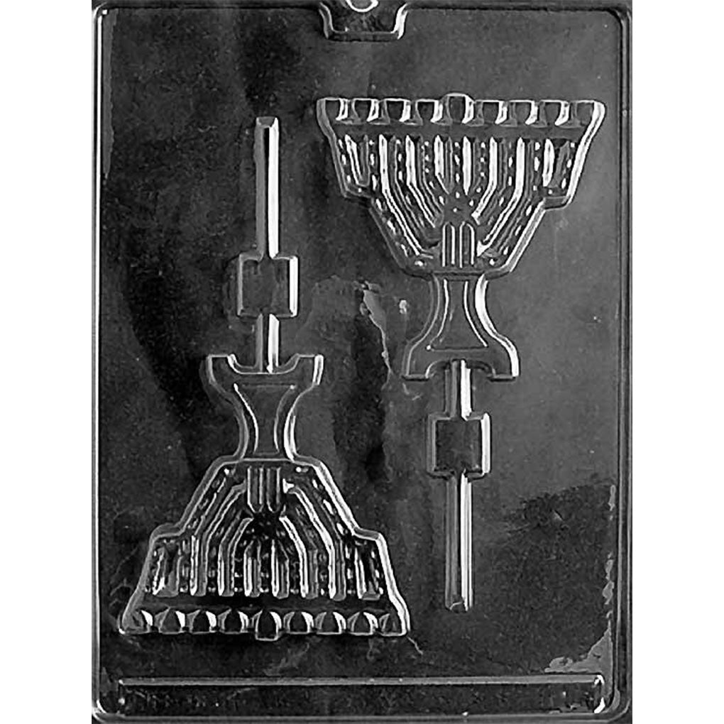 Clear plastic chocolate lollipop mold photographed on a dark background with two large menorah-shaped cavities, each with a built-in stick channel.