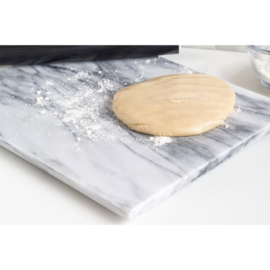 Dough and flour on white marble pastry board, illustrating its smooth, cool surface for rolling and shaping.