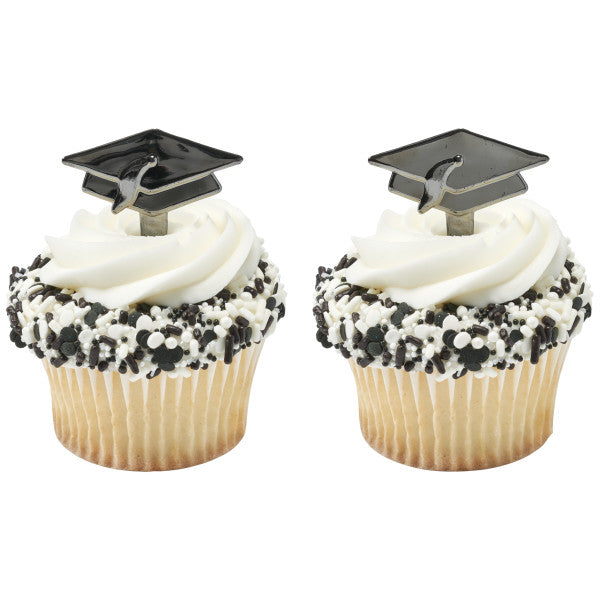 Two vanilla cupcakes with white frosting, black and white sprinkles, and black graduation cap toppers with tassels.