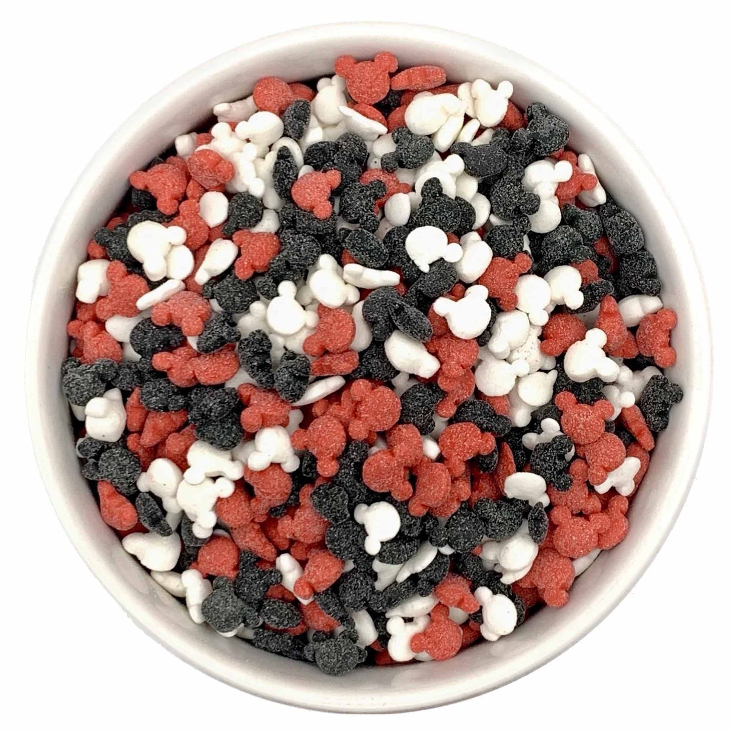 White bowl filled with red, black, and white Mickey Mouse-shaped sprinkles, showing small silhouette shapes with a lightly textured sugar coating.