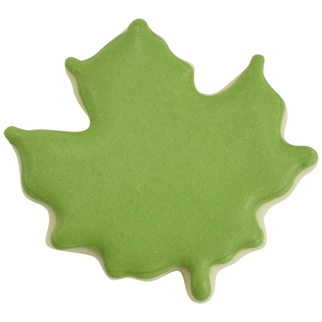 Mini maple leaf-shaped sugar cookie decorated with smooth green icing.