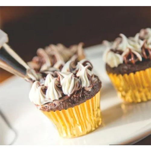 Chocolate mini cupcake in a gold foil baking cup topped with piped frosting, with additional cupcakes blurred in the background.