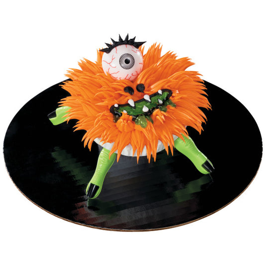 Decorated cupcake topped with orange fur frosting, eyeball, and green finger picks creating a spooky monster.