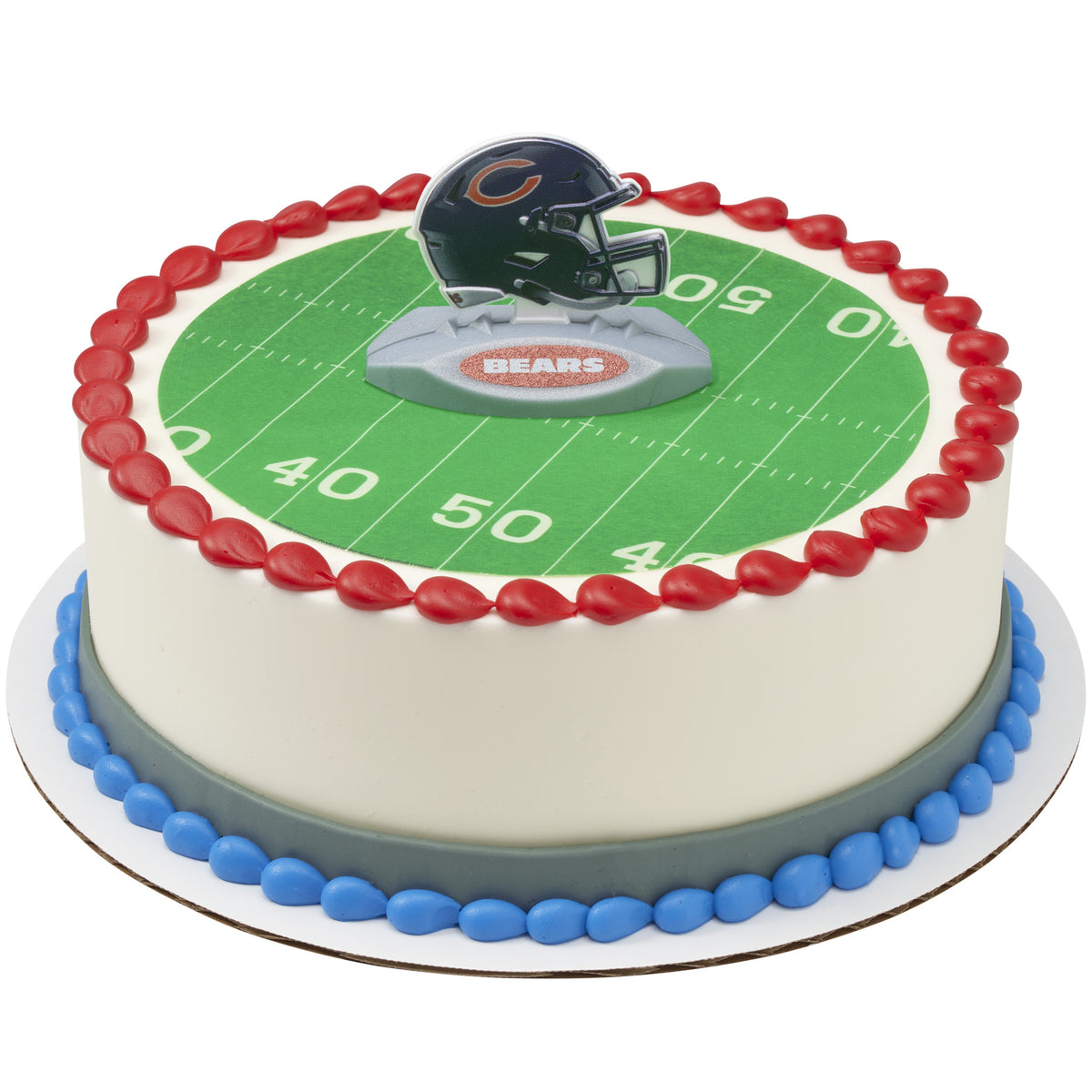 A round cake decorated with a green football field print, red piped border, blue base trim, and a Chicago Bears helmet topper on top.