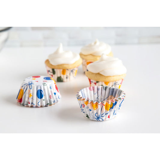 Party Balloon Mini Baking Cups shown open and filled with bite-sized cupcakes topped with white frosting