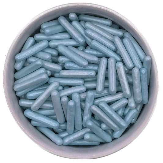 Close-up of pearlized blue edible rod sprinkles in a white bowl, showing elongated shape and shimmered surface ideal for cake and cookie decorating.