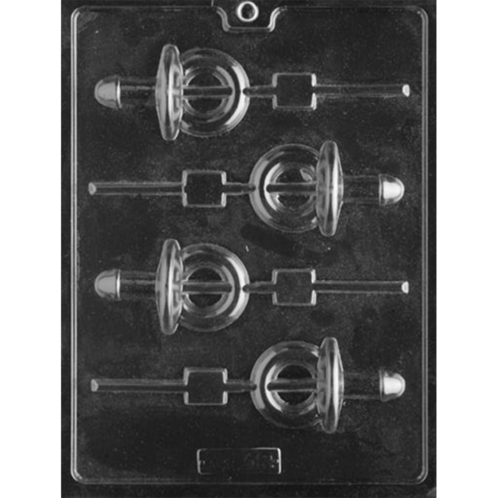 Clear plastic chocolate lollipop mold photographed against a dark background, featuring four penis-shaped pacifier cavities with round shields and channels for sucker sticks.