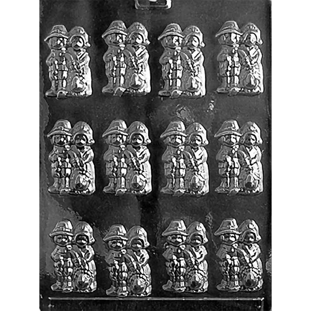 Clear plastic chocolate mold with twelve cavities featuring a pilgrim couple holding a turkey, with detailed hats and clothing, shown on a dark background.