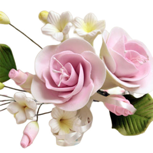 Pink dog rose gum paste flower spray with two soft pink rose blooms, tiny white flowers, green leaves, and pale pink buds on wired stems.