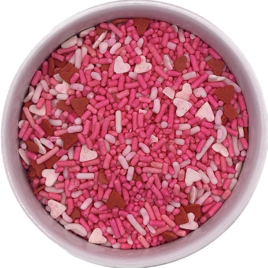 Pink, white, and red heart-shaped and jimmie-style sprinkles in a 4 oz container, ideal for Valentine's Day and romantic dessert decorating.