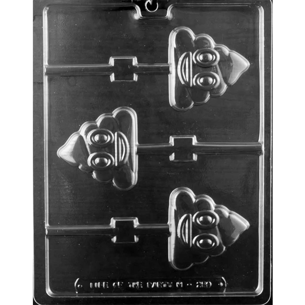 Clear plastic chocolate lollipop mold with three poop emoji shaped cavities featuring raised eyes, smiling faces, swirled poop outlines, and lollipop stick channels on a dark background.