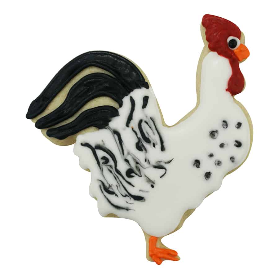 Decorated rooster cookie with white icing, black tail feathers, and red and orange details.
