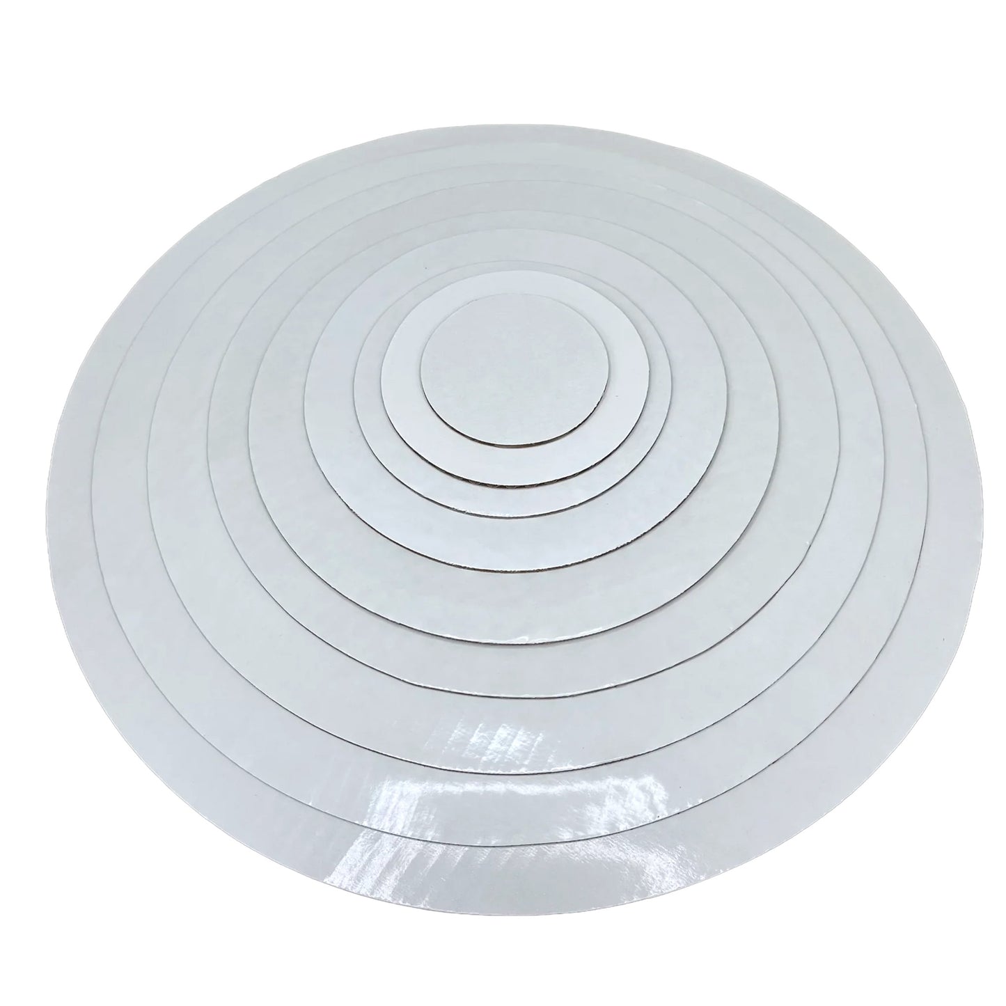 Stack of white round wax-coated cardboard cake boards in assorted sizes on a white background.