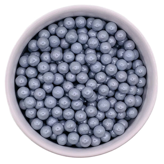 Close-up of 7mm silver sugar pearls in a bowl, with a metallic candy coating for decorating cakes, cupcakes, and cookies.