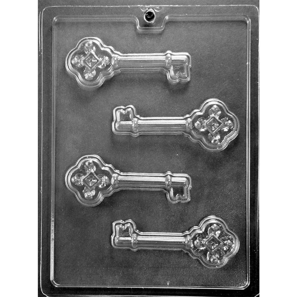 Clear plastic chocolate mold photographed on a dark background with four skeleton key-shaped cavities, featuring ornate key heads, ridged shafts, and traditional key bits.