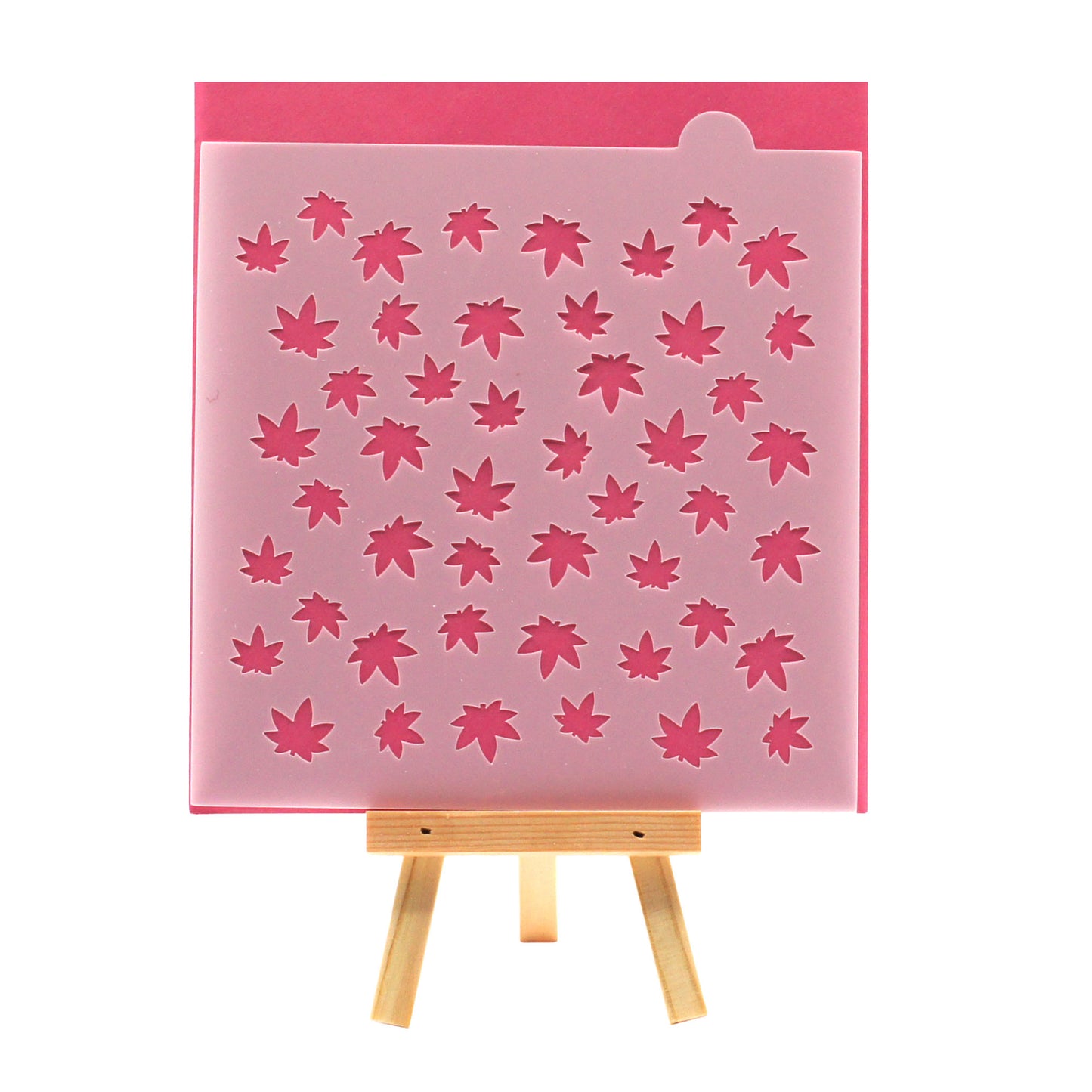 Small marijuana leaf pattern cookie stencil on a pink background, shown on a small wooden easel.