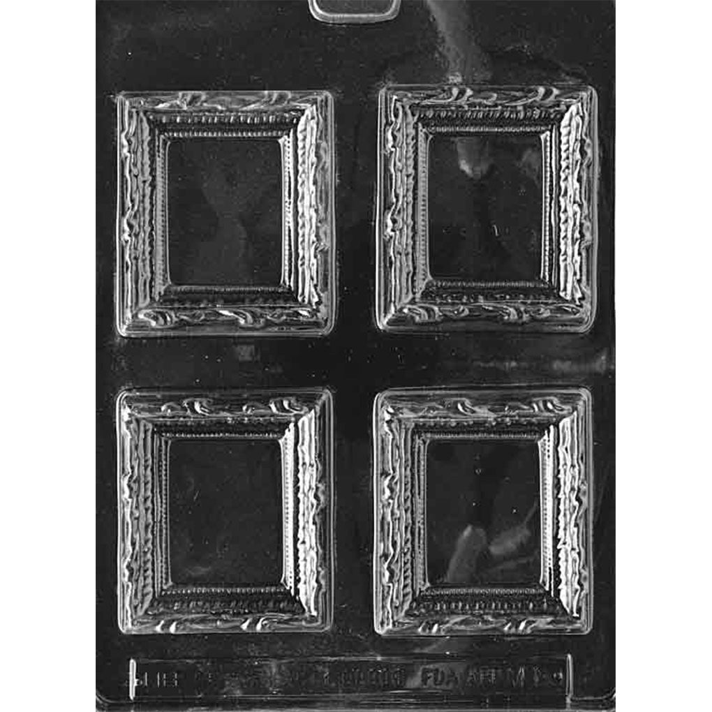 Clear plastic chocolate mold photographed on a dark background with four ornate picture frame cavities, each with a raised decorative border and a recessed rectangular center.
