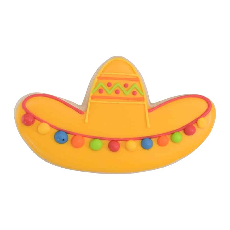 Decorated sombrero cookie with yellow icing, red trim, and colorful pom-pom details.