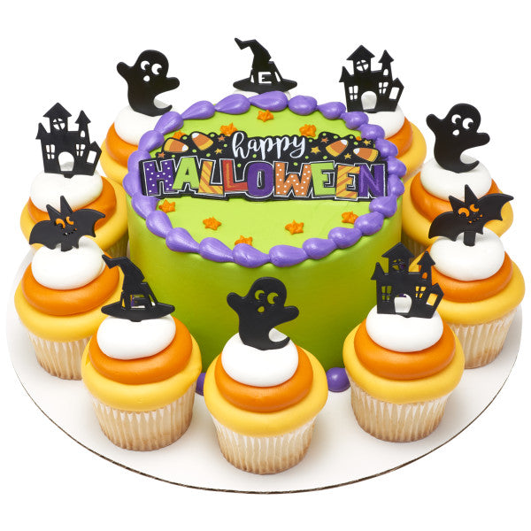 Round green Halloween cake with coordinating cupcakes topped with ghost, haunted house, bat, and witch hat picks arranged around the edge.