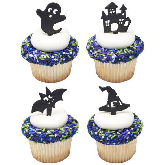 Cupcakes topped with white frosting, colorful Halloween sprinkles, and black spooky picks in ghost, bat, haunted house, and witch hat shapes.