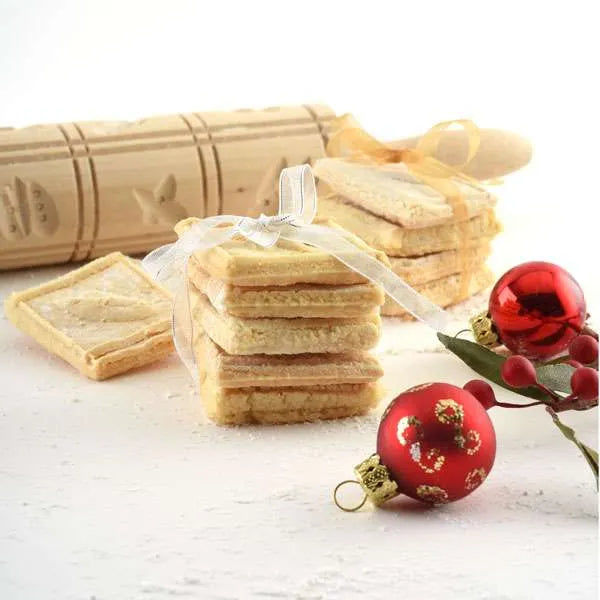 Finished embossed cookies tied with ribbon near the rolling pin and festive decorations.
