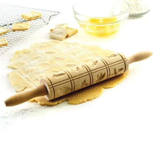 Springerle rolling pin embossing cookie dough on a floured surface.