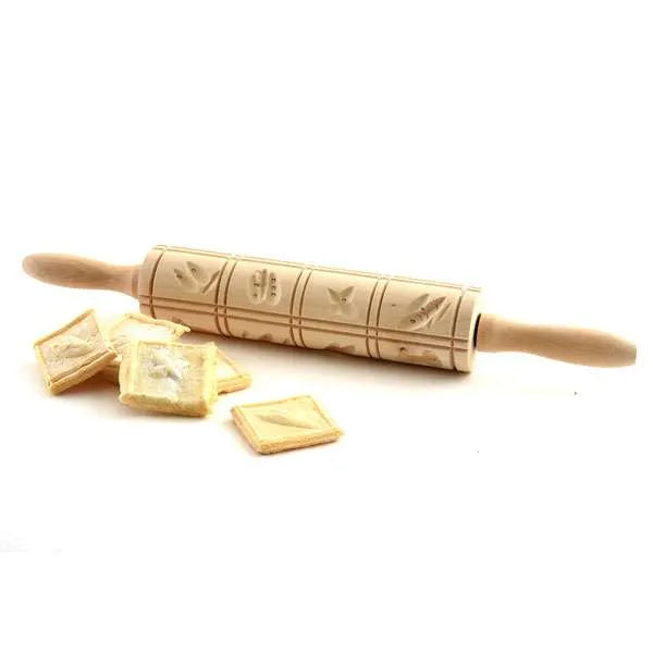 Springerle rolling pin placed beside square cookies showcasing the pressed designs.