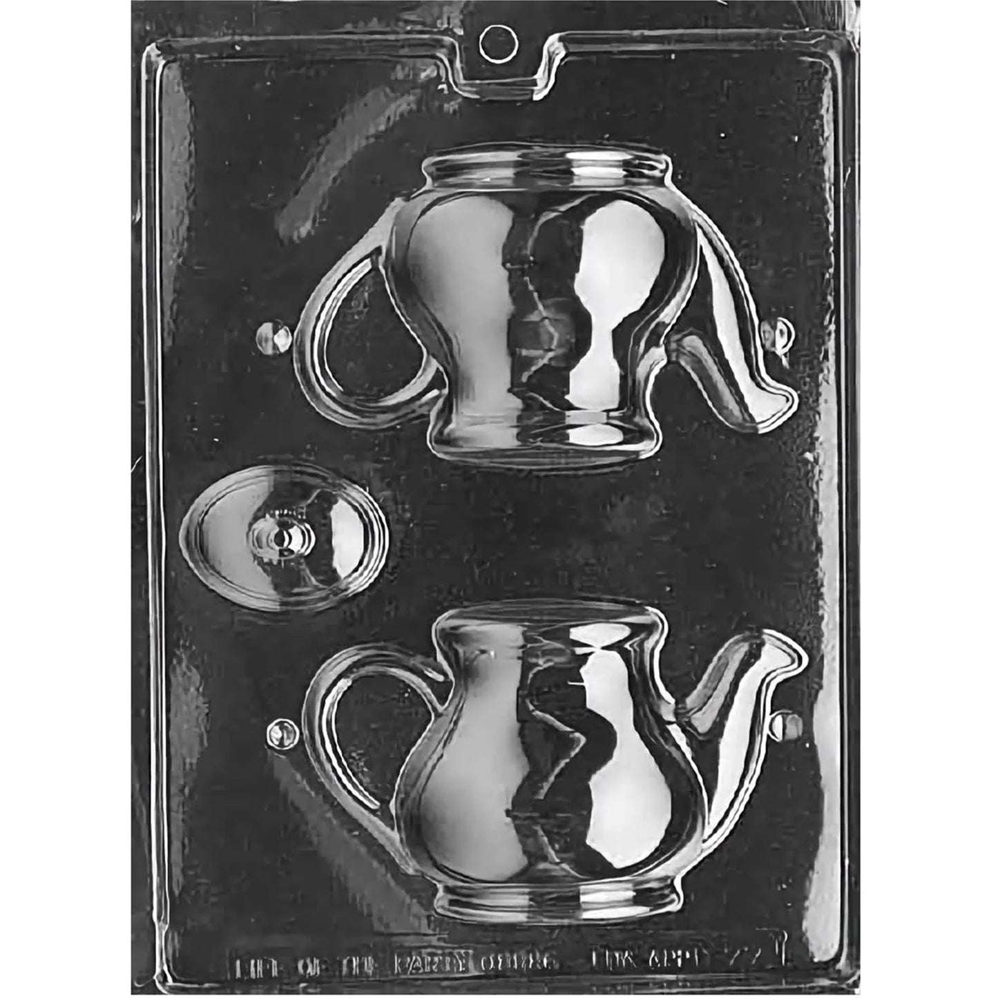 Clear plastic 3D chocolate mold with teapot-shaped cavities and a separate round lid cavity, shown on a dark background. The teapot design includes a curved handle, spout, and rounded body.