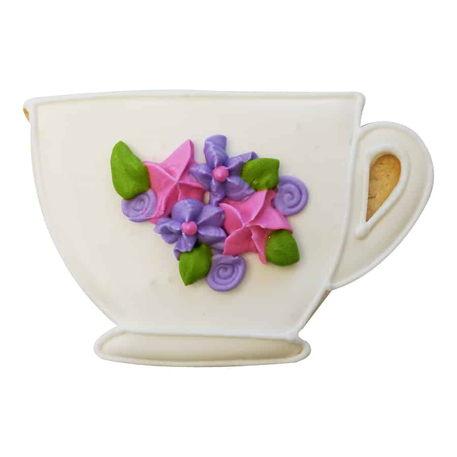 Decorated teacup-shaped cookie with white icing and delicate pink and purple floral details.