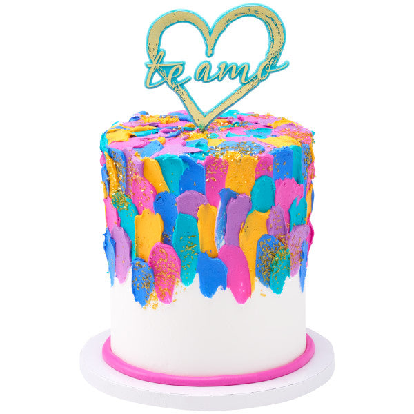 Single-tier ombre cake with piped floral accents and red "Te Amo" heart topper.