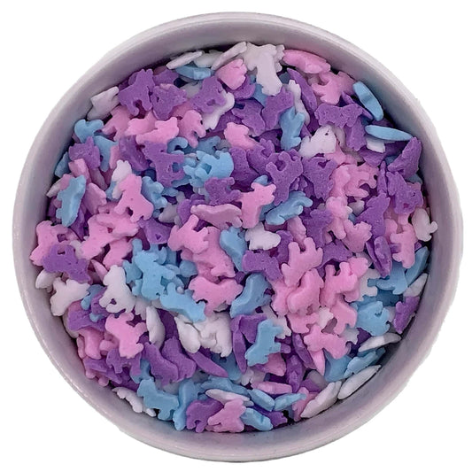 Pastel unicorn-shaped sprinkles in pink, purple, blue, and white inside a round container, perfect for decorating cupcakes and birthday treats.