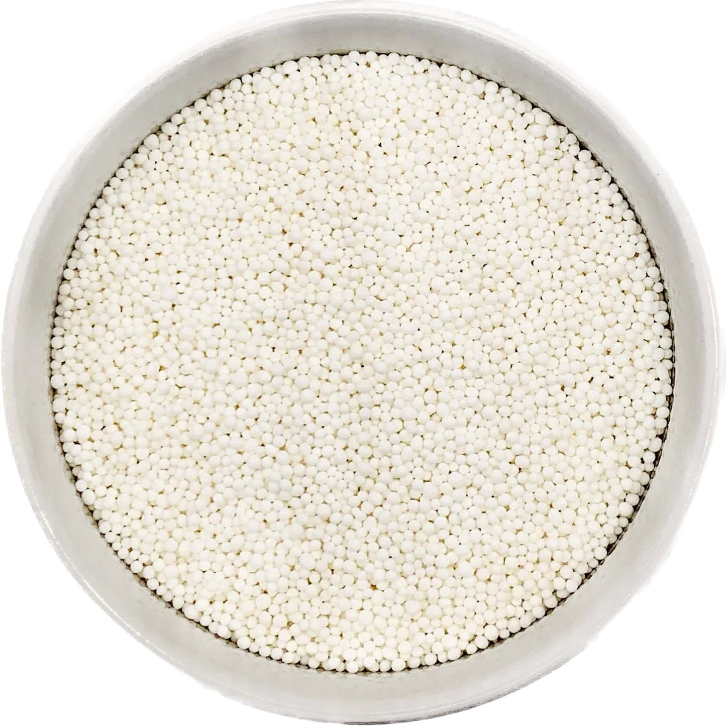 Bowl of bright white nonpareil sprinkles on a white background.