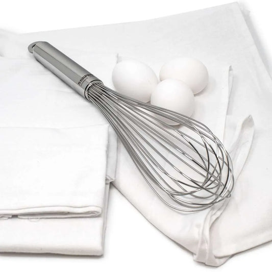 Stainless steel whisk and three white eggs on flour sack towels.