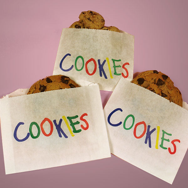 Three white cookie bags with colorful "COOKIES" lettering, each filled with chocolate chip cookies, displayed on a pink background.