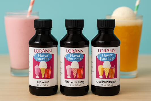 Three LorAnn Flavor Fountain bottles in Red Velvet, Pink Cotton Candy, and Hawaiian Pineapple, with milkshakes in the background.