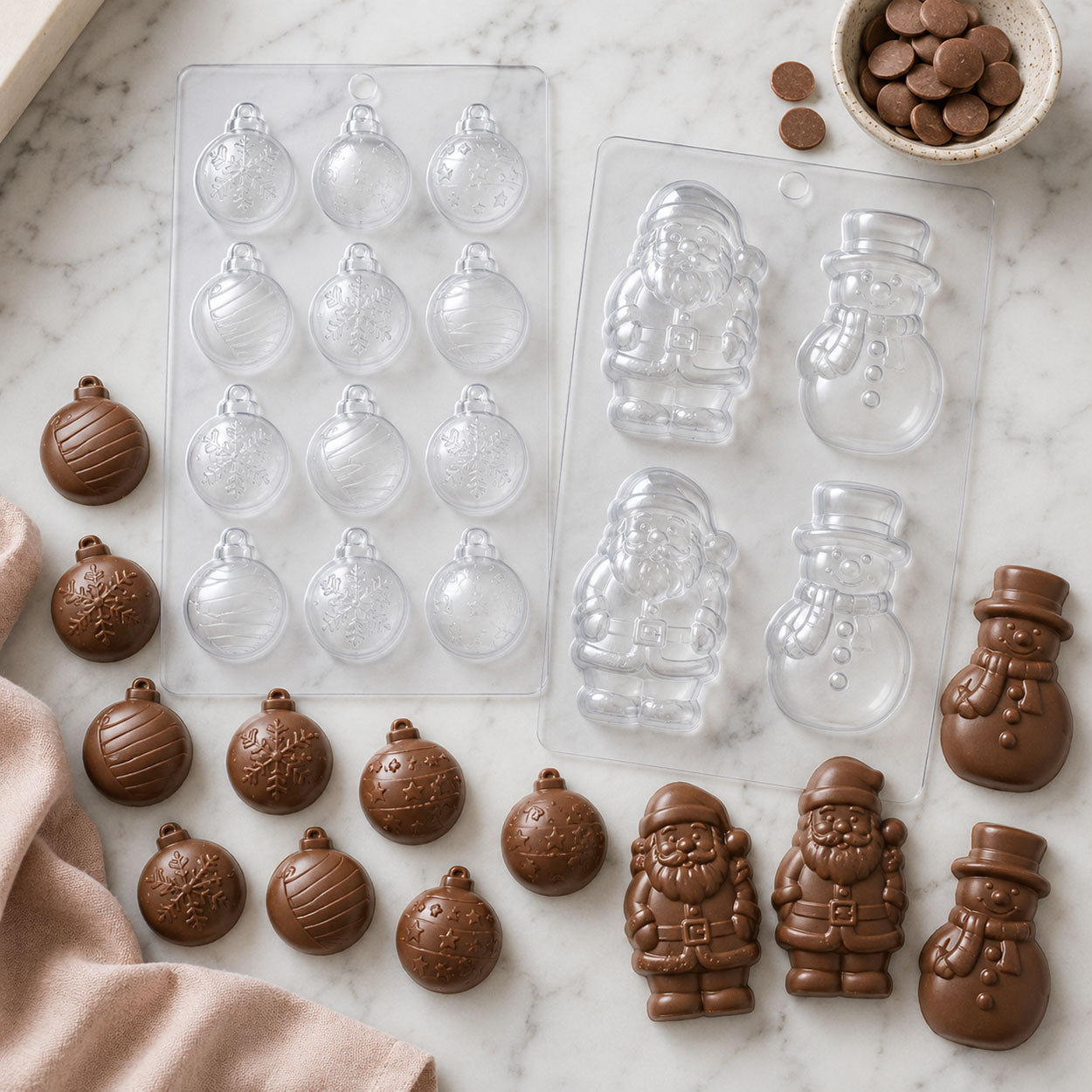 Christmas chocolate candy molds featuring ornament, Santa Claus, and snowman shapes with finished milk chocolate candies, chocolate melts, and holiday candy-making supplies.