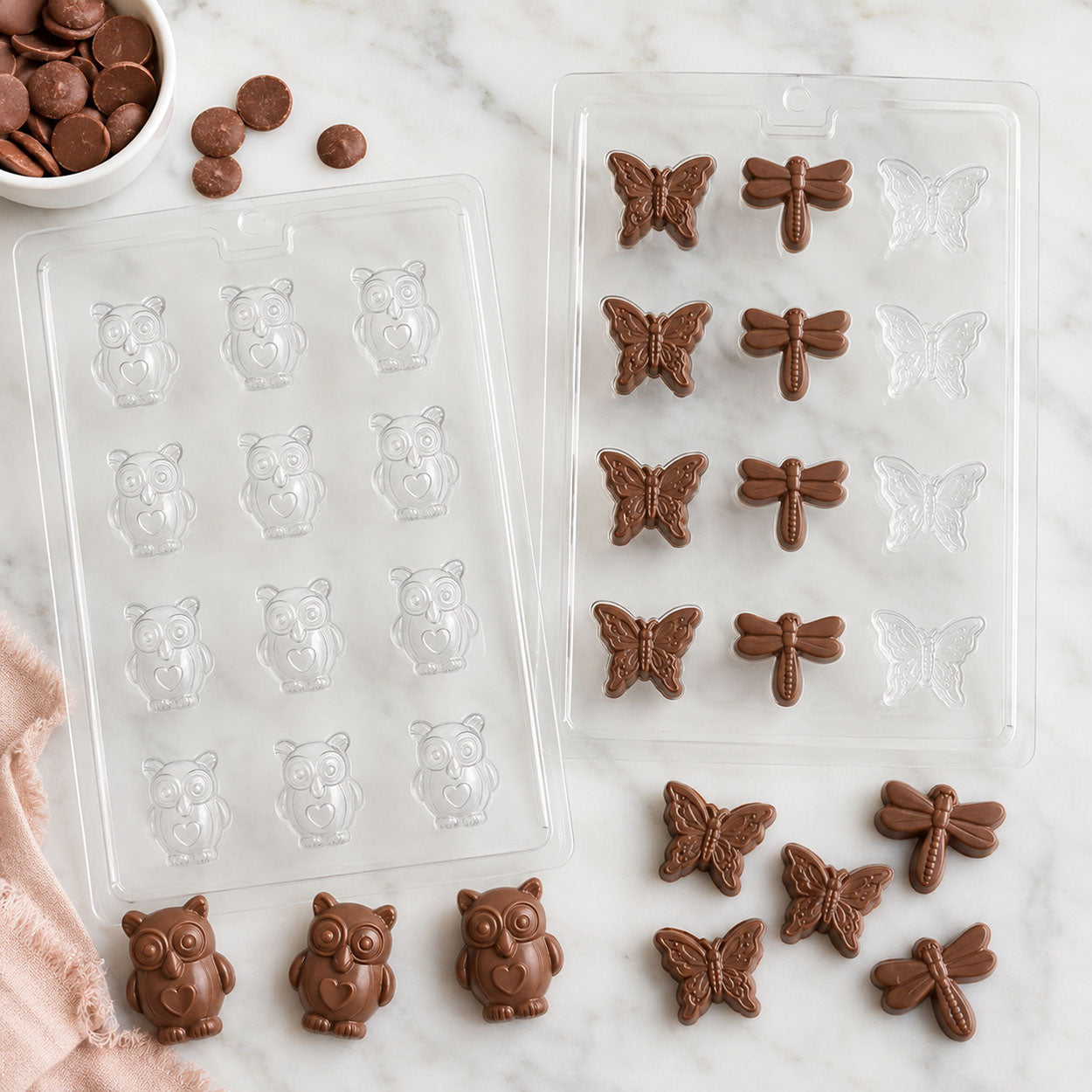 Chocolate candy molds featuring owl, butterfly, and dragonfly shapes with finished milk chocolate candies, candy melts, and molded chocolate pieces.