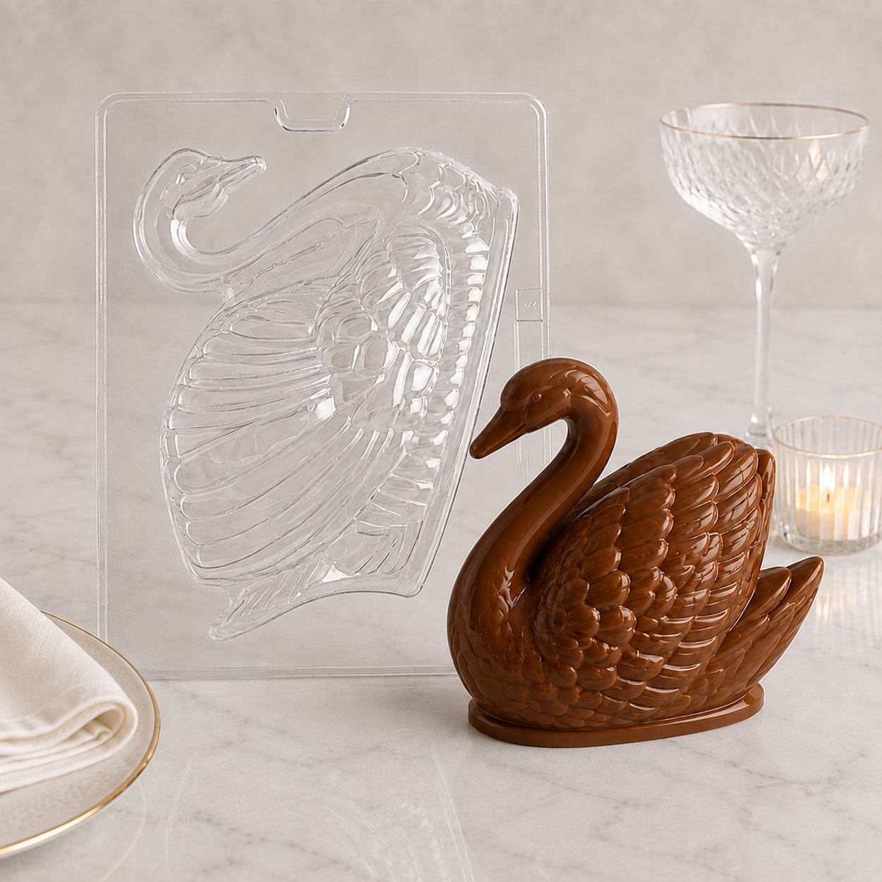 Swan chocolate mold with finished 3D chocolate swan centerpiece, displayed on a marble surface with elegant table setting.