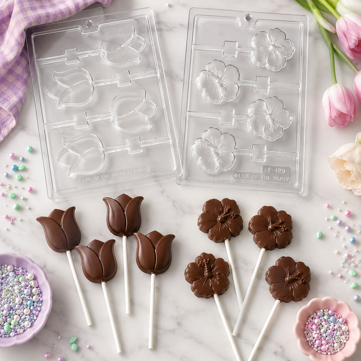 Chocolate flower and tulip lollipop molds with finished chocolate flower pops, tulip pops, pastel sprinkles, and spring baking decorations.
