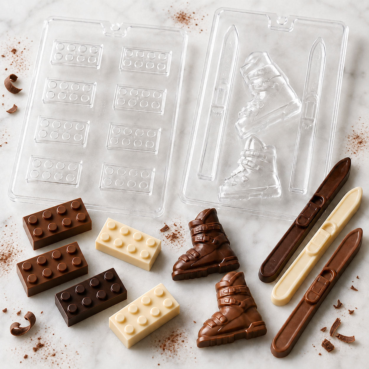 Chocolate molds for building blocks, ski boots, and ski lollipops with finished milk, dark, and white chocolate candies.