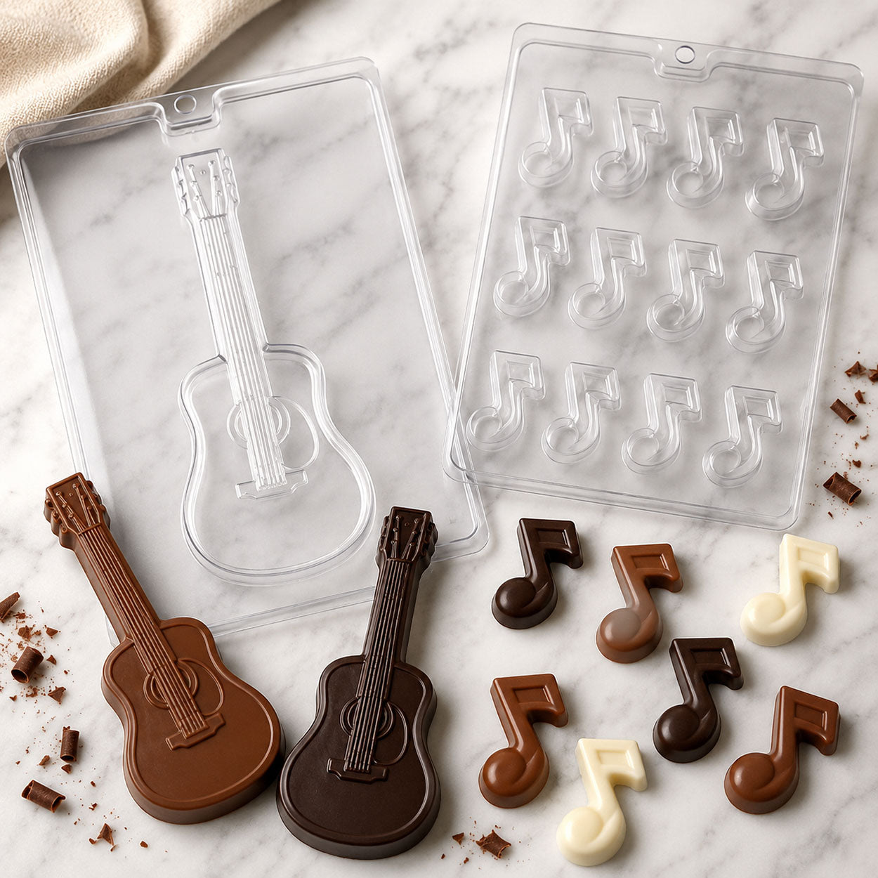 Chocolate molds for guitar and music note candies with finished milk, dark, and white chocolate guitar shapes and musical notes for music-themed treats.