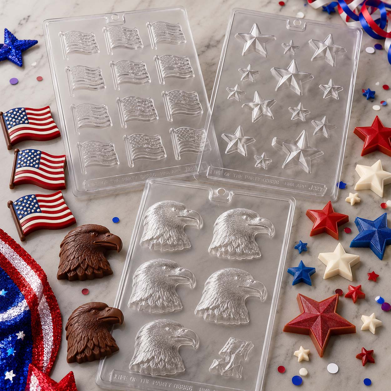 Patriotic chocolate molds with American flags, stars and bald eagle candies displayed on a marble surface with festive red, white and blue decorations.