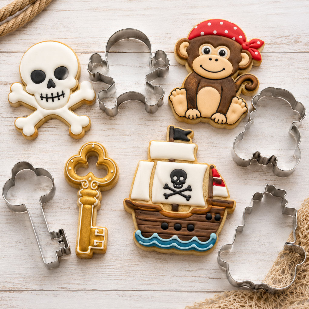 Pirate-themed cookie cutters and decorated cookies shaped like a skull and crossbones, pirate monkey, treasure key, and pirate ship.