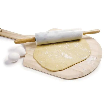 A marble rolling pin with wooden handles, sitting on a wooden pizza peel with a rolled-out dough beneath it. Marble pins are known for their weight and cool surface, making them excellent for working with pastry doughs. Two eggs are placed nearby as props.