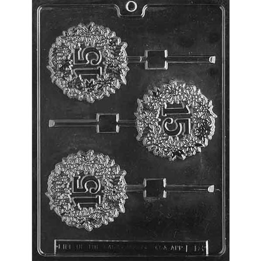 Clear 15th in Wreath Chocolate Lollipop Mold photographed against a black background with three round cavities featuring raised 15 numerals inside detailed floral wreaths.