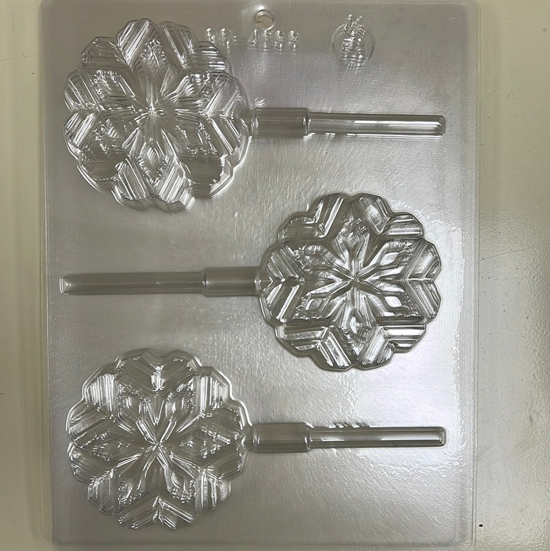 This is a plastic mold designed for making snowflake-shaped lollipops. The mold has three cavities, each with a detailed snowflake design and a built-in stick holder for easy lollipop creation.